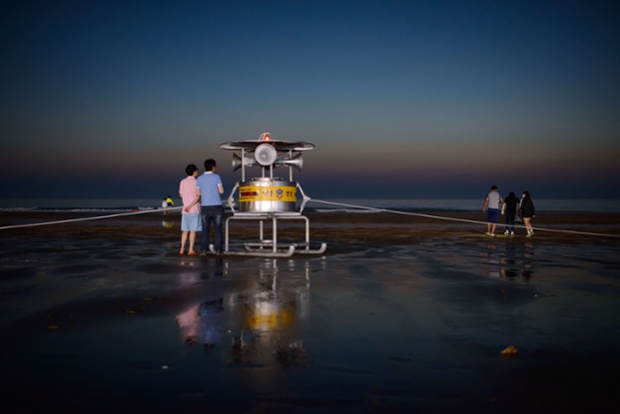 People walk near a beach safety broadcasting system on Mallipo beach in South Korea.