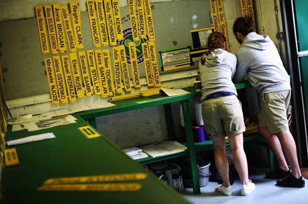 Member of staff study signs displaying the names of competitors used for the scoreboards at Wimbledon.
