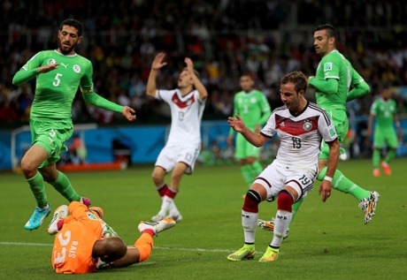 Goalkeeper Rais M'Bolhi of Algeria makes a double save from Toni Kroos and Mario Goetze.