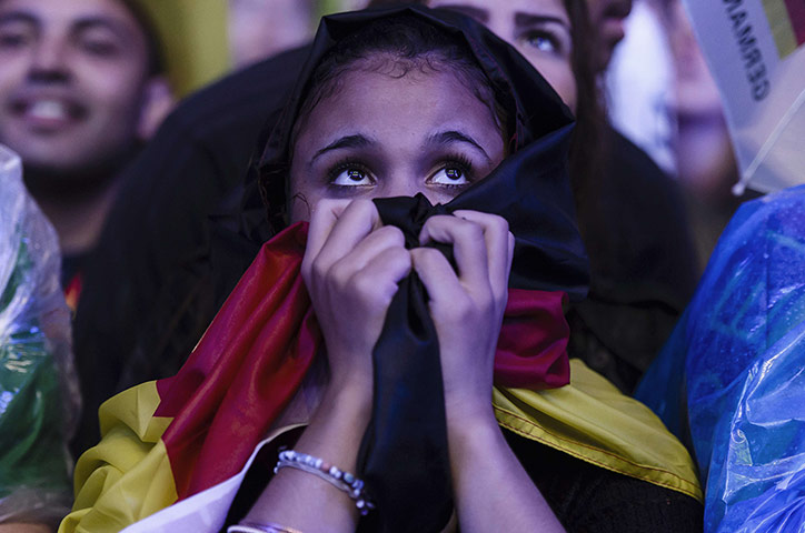 belo horizonte germany: A fan covered in a German flag watches t