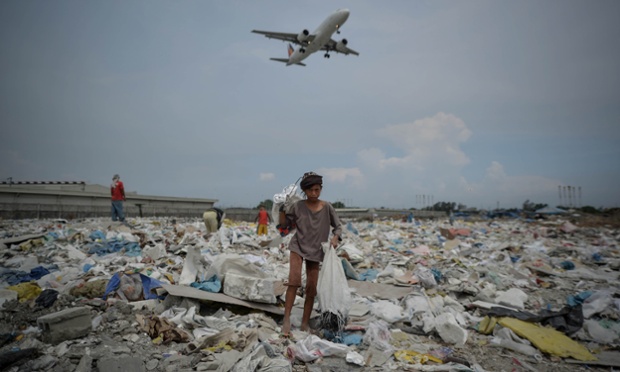 A plane flies overhead as a girl looks for recyclables at a garbage dump during World Environment Day in Paranaque, Philippines.