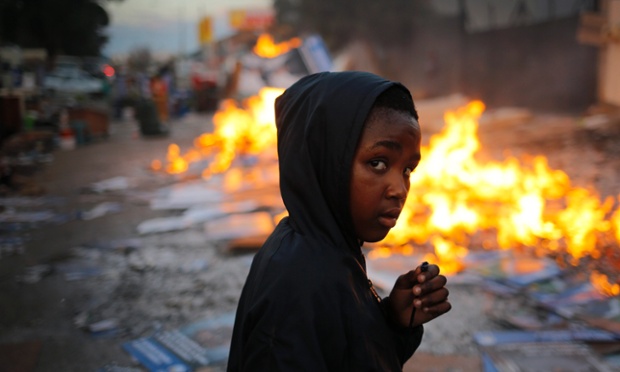 A young boy walks past a burning fire used to keep evicted families warm overnight after police and private security evicted families from a commercial property in Johannesburg, South Africa.
