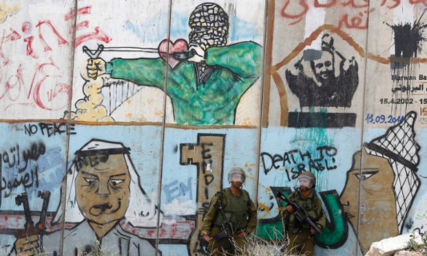 Israeli soldiers stand guard in front of the controversial Israeli barrier during a protest by Palestinians in solidarity with prisoners on hunger strike, at Qalandia checkpoint near the West Bank city of Ramallah.