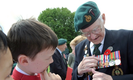 Veteran Frederick Wyatt, 92, from the 48th Royal Commando Dragoon Guard, explains the meaning of his decorations to a choir boy of the St John's College Choir of Cambridge, in Bayeux.