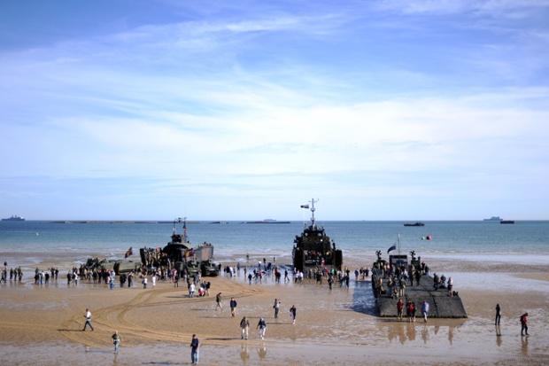 People walk aboard ships set up on the beach in Arromanches prior to a joint French-Dutch D-Day commemoration ceremony in Arromanches, Normandy.