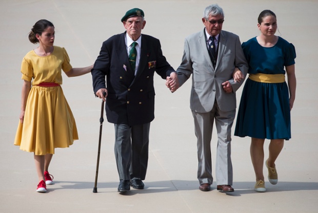French veteran Leon Gautier of the Kiieffer commando (2-L) and German veteran, paratrooper Johannes Borner (2-R) walk hand in hand on Sword Beach.