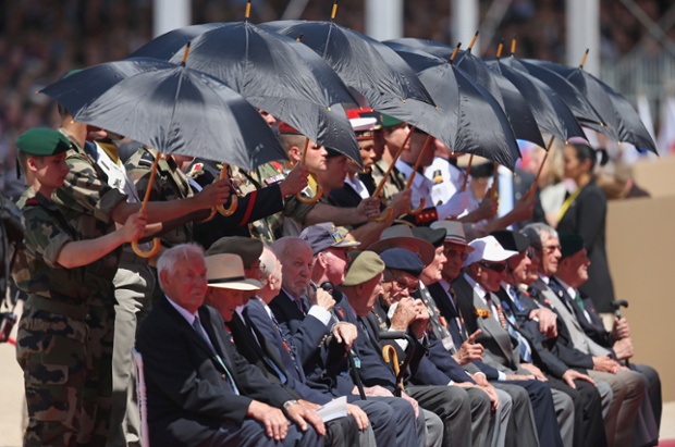 D-day veterans are shielded from the sun at the main international ceremony at Sword Beach.