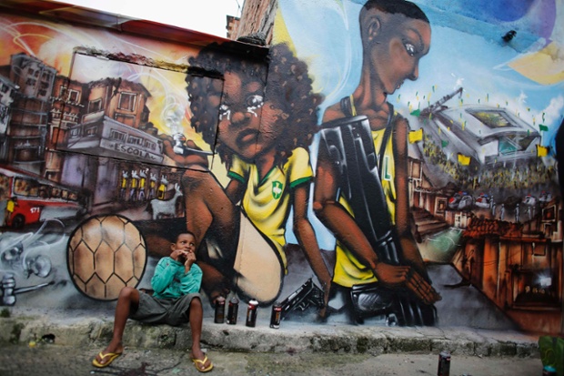 Ryan, 9, eats in front of graffiti painted by members of OPNI n the Vila Flavia of Sao Paulo