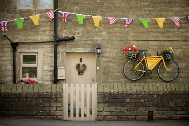 A yellow, flower-clad bike adorns a stone cottage in Holmfirth