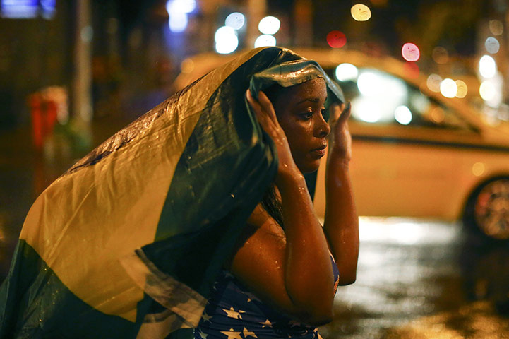 20 Photos: A fan walks in the rain after watching Brazil's loss against Germany