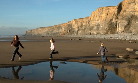 A family running on the beach at Traeth Mawr in Wales