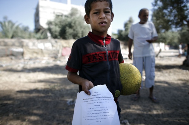 A Palestinian boy shows a flyer dropped over Gaza City by the Israeli army urging residents to evacuate their homes.