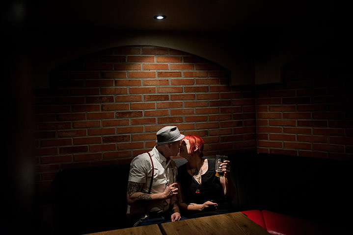 Weekend - Skinheads : man in hat with tattoos and girl with red hair kissing in dimly lit bar