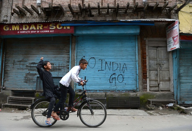 Kashmiri boys ride a bicycle during a one-day strike against Israeli military operations in Gaza, in Srinagar, India