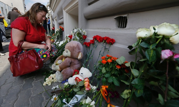 A woman grieves for victims of the crash near the floral tributes placed at the the Dutch embassy in Moscow, Russia.