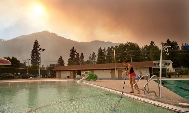 Jana Witkowski, a lifeguard at the Leavenworth swimming pool in Washington cleans ash and burned embers from the bottom of the pool that fell from the Chiwaukum forest fire.
