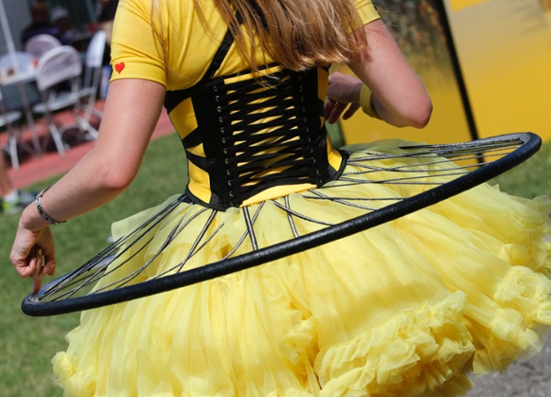 An entertainer wears a dress in the colors of the overall leader's yellow jersey adorned with a bicycle wheel prior to the start of the tenth stage of the Tour de France cycling race over 161.5 kilometers (100.4 miles) with start in Mulhouse and finish in La Planche des Belles Filles, France.