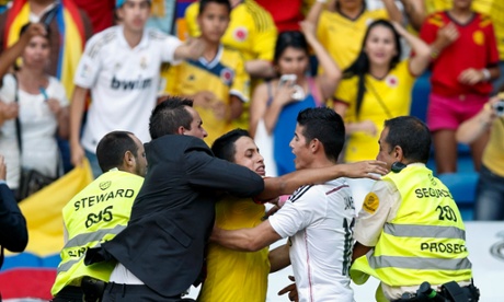 A fan is grabbed by security guards as he tries to embrace the new Real Madrid player James Rodríguez