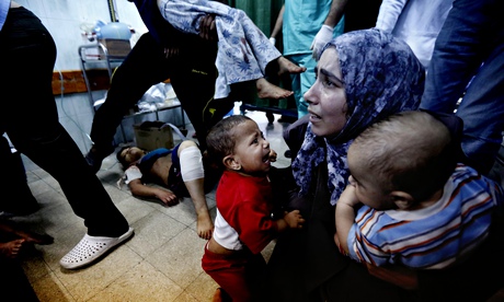A Palestinian medic holds two children hurt in an Israeli strike on a UN school in Beit Hanoun, Gaza