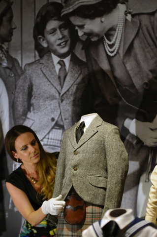 A member of staff poses with a tweed jacket, leather sporran and kilt worn by Prince Charles