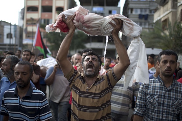 A Palestinian man hold-up the body of one-year-old baby Noha Mesleh, who died of wounds sustained after a UN school in Beit Hanun was hit by an Israeli tank shell, during her funeral in Beit Lahia, northern Gaza Strip