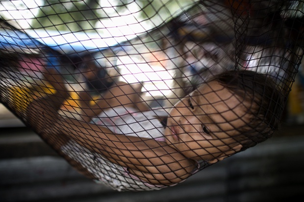 A child rests on a hammock along a street in Manila. Optimism is soaring that the Philippines is finally becoming an Asian tiger economy, but critics caution a tiny elite that has long dominated is amassing most of the new wealth while the poor miss out.