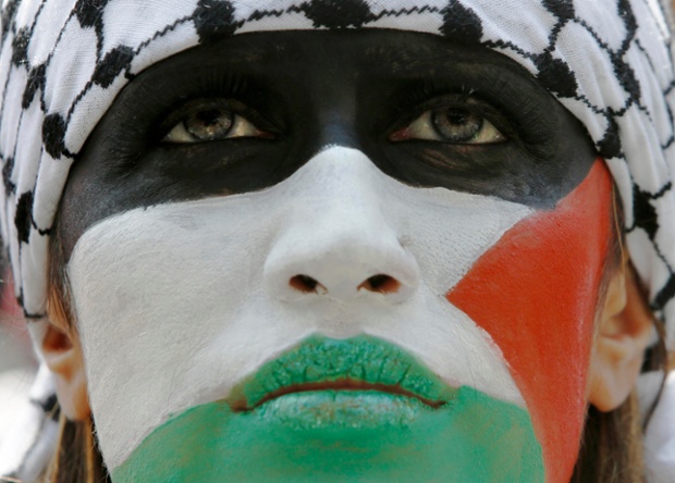 London, UK: A demonstrator with their face painted in the colours of the Palestinian flag protests outside the Israeli embassy