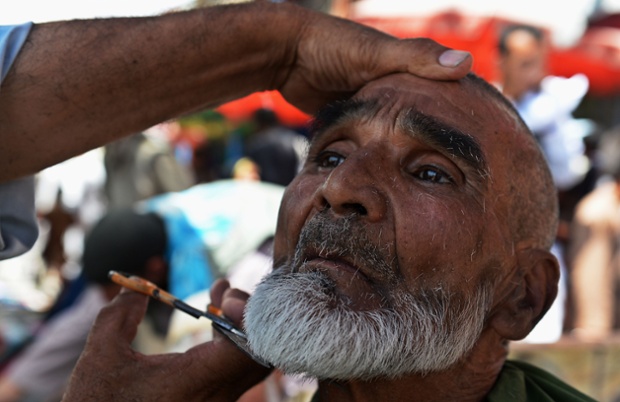 Kabul, Afghanistan: An Afghan barber serves a customer at a market ahead of the Eid-al Fitr festival which marks the end of the holy Islamic month of Ramadan.