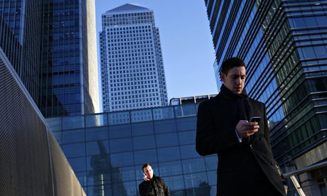 A worker looks at his phone at the Canary Wharf business district in London