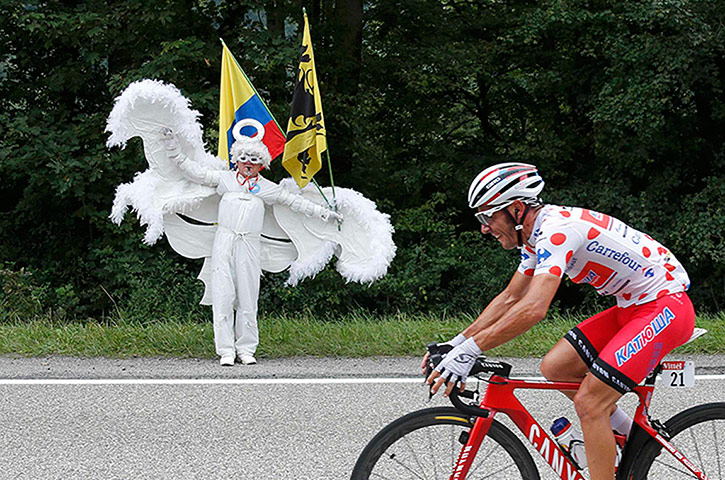 Watching the TDF2014: Joacquim Rodriguez of Spain cycles past a fan dressed in angel