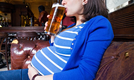 Pregnant woman drinking a pint of beer in pub