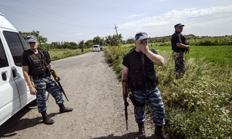 Pro-Russian militants stand guard as investigators  work at the crash site of the Malaysia Airlines Flight MH17