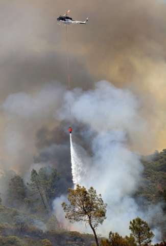 A helicopter drops water on Butts Fire