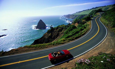 Person driving convertible on a coastal highway in California.