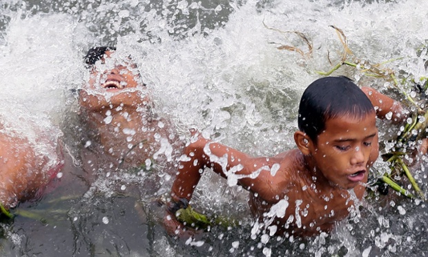 Filipino children frolic against strong waves along the seawall in Tondo slum area in Manila