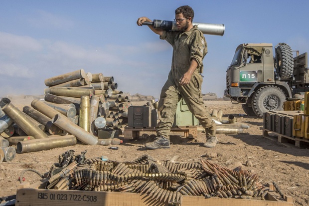 An Israeli soldier carries a shell