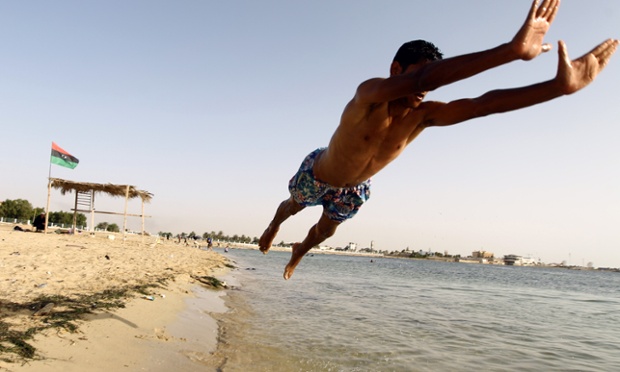 A Libyan man jumps in the water to go swimming at a beach in the eastern city of Benghazi
