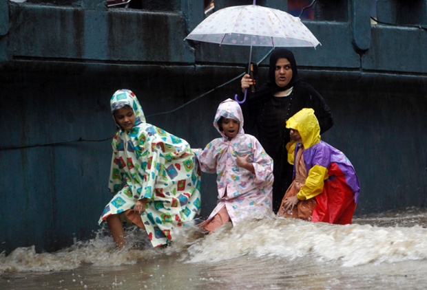 Paddling on the school run: Indian schoolgirls wade through a waterlogged street in Mumbai, India, as heavy rainfall in the city causes flooding in several areas.