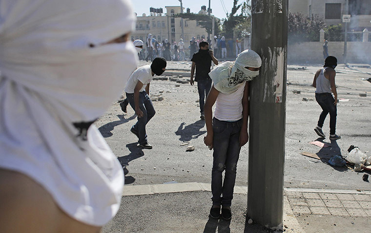 20 photos: A Palestinian stone-thrower takes cover during clashes with Israeli police