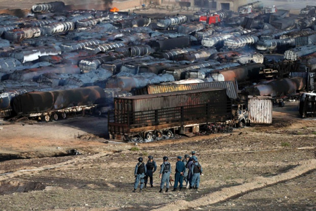 Kabul, Afghanistan: Afghan policemen stand at the site of burning fuel trucks after an overnight attack by the Taliban