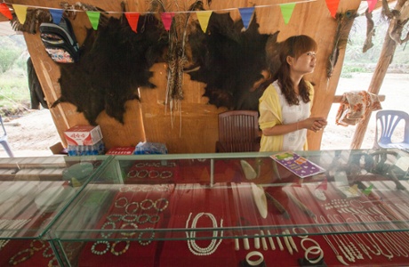 A woman is seen selling ivory products with two bear skins flanking a wild cat skin behind her on the wall, at an exotic wildlife restaurant for Chinese tourists in the town of MongLa, Shan State Special Region Four, Burma, 04 April 2014.
