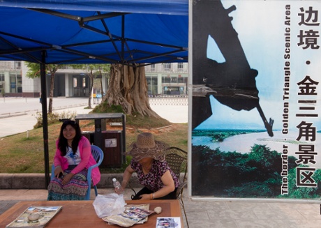 Two young women run a booth for tourists next to the Chinese border with Burma advertising tours to the 'Golden Triangle Scenic Area', in Daluo, the border town with Burma, Xishuangbanna, Yunnan Province, China.