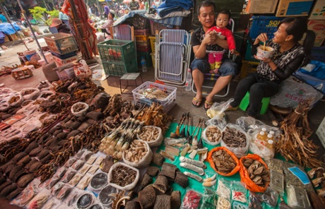 A trader of illegal wildlife products is seen with his family at a covered market in the town of MongLa, Shan State Special Region Four, Burma