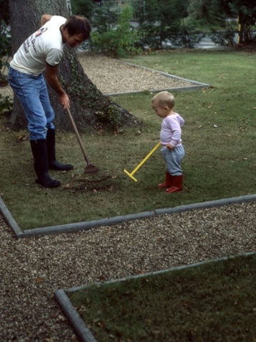 son helping father rake the garden