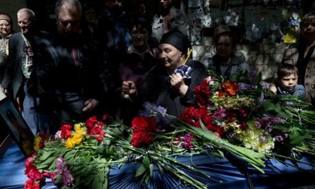 The mother of Dmitriy Nikityuk, a Cossack, holds a candle next to his coffin during his funeral in Odessa, Ukraine, on 8 May, 2014. Nikityuk died in the burning trade union building fire that killed most of the 40 people that died after riots erupted.(AP Photo/Vadim Ghirda)