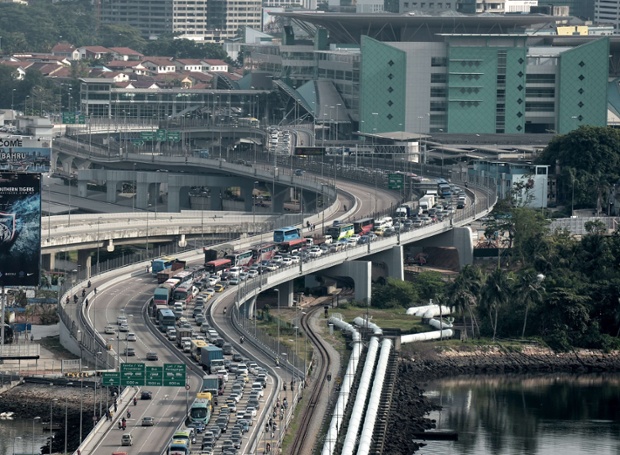 A massive jam disrupts rush-hour traffic into Singapore as bus drivers staged a strike this morning.