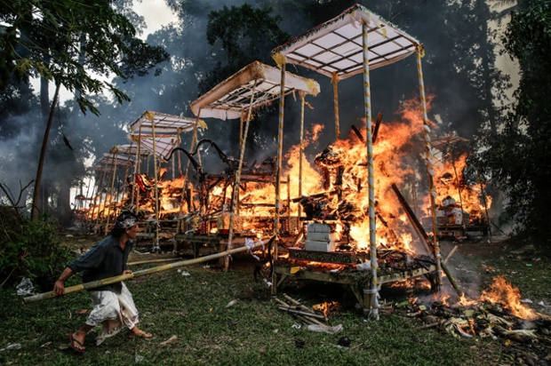 A man tends a sarcophagus in the shape of a buffalo during a Balinese Hindu mass cremation in Ubud, Bali, Indonesia. More than 100 corpses were cremated in the ceremony known as Ngaben Masal (Mass Cremation). Taking place every 4 years in Singakerta Village, it is one of the most important ceremonies for Balinese Hindu people.
