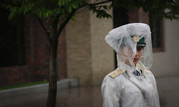 A traffic controller stands in her rain gear Friday, July 25, 2014 in Pyongyang, North Korea. A typhoon was approaching North Korea on Friday as the country began its rainy season.