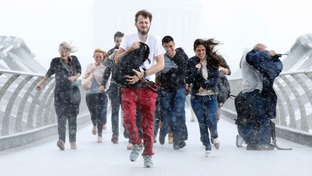 London: Pedestrians are caught in torrential rain caused by the tail-end of Hurricane Bertha while walking along Millennium Bridge.