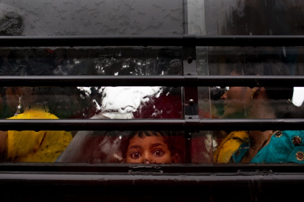 New Delhi, India: A child looks out a bus window as as monsoon rain pours down.